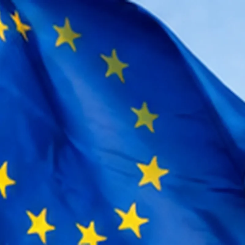 O que muda com o Regulamento dos Serviços Digitais e a nova lei portuguesa 2 Bandeira da União Europeia junto a edifícios, enquadrando o Regulamento dos Serviços Digitais.